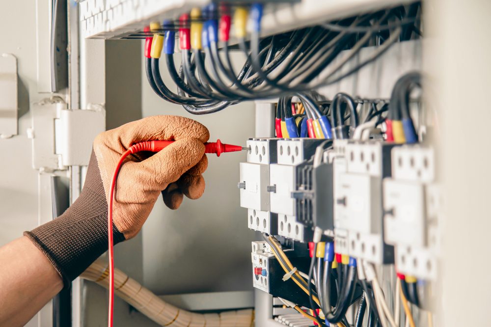 Safety in Control Cabinet Construction - Electrical engineer checking the operation of electrical control cabinet, maintenance concept.