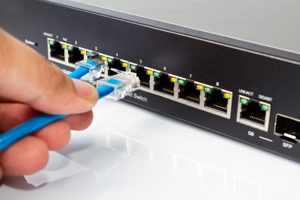 RJ 45 connector: LAN network switch with ethernet cables plugging in on white